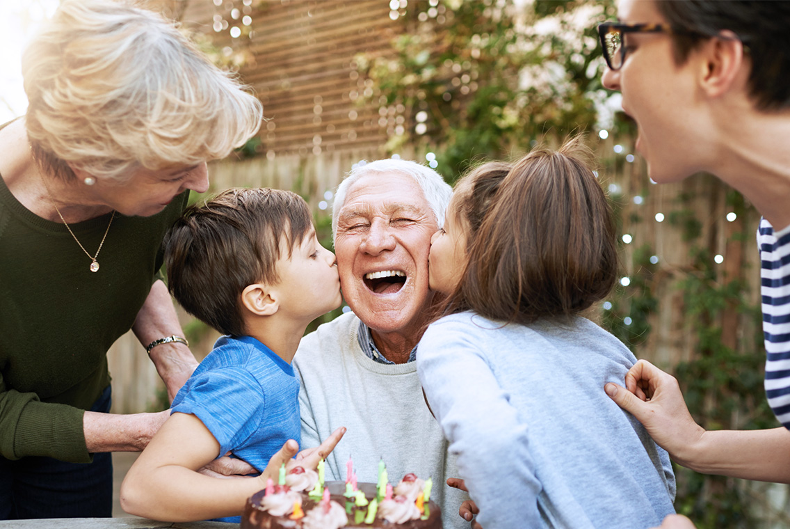 Homme âgé avec sa famille autour d'un gâteau d'anniversaire