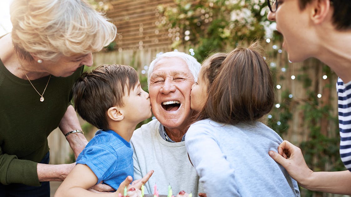 Homme âgé avec sa famille autour d'un gâteau d'anniversaire