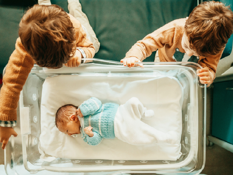 Enfants qui regardent un berceau avec un nouveau né 