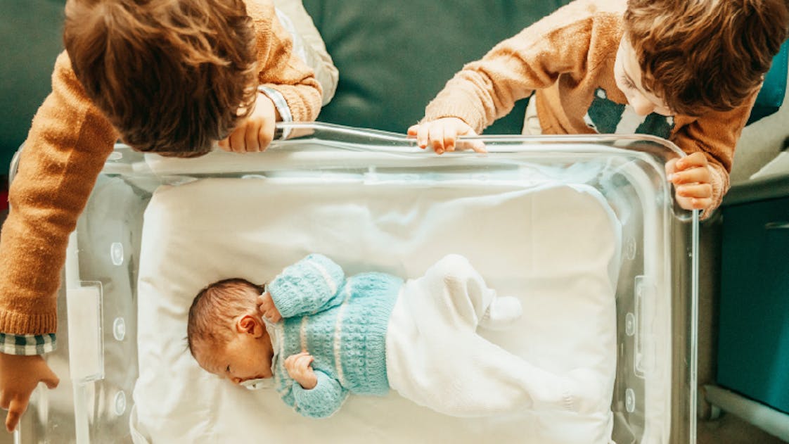 Enfants qui regardent un berceau avec un nouveau né